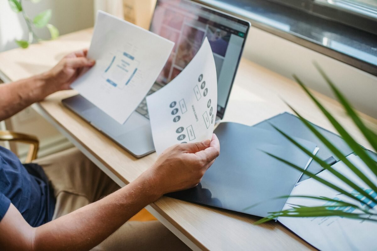 Person in front of a laptop holding financial papers.