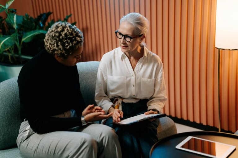 Two women sitting on couch having a conversation.
