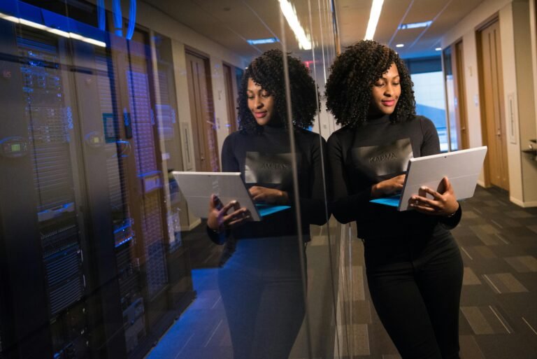 Woman standing outside of technology server room holding a tablet computer