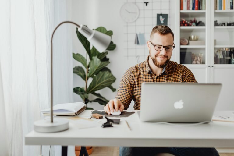 Man working at desk while looking at laptop screen.