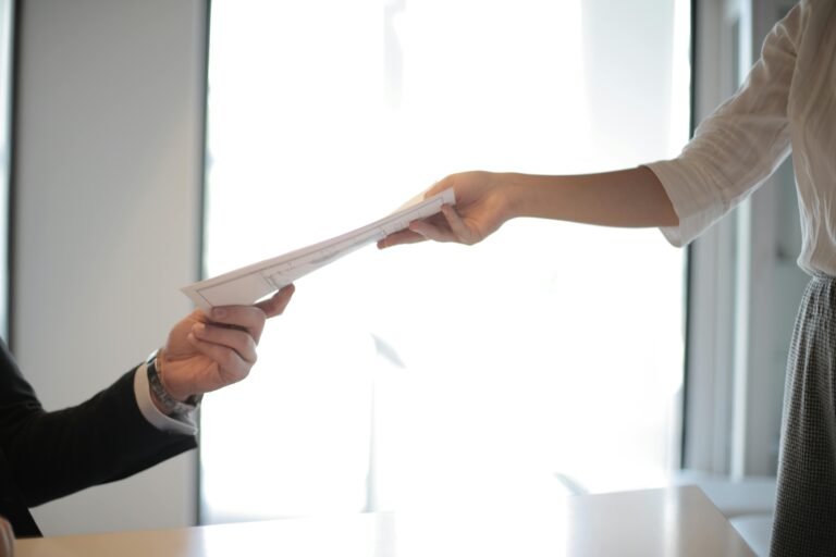 Person handing another person a piece of paper.