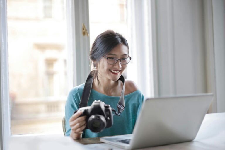 Adult woman with camera looking at a laptop computer
