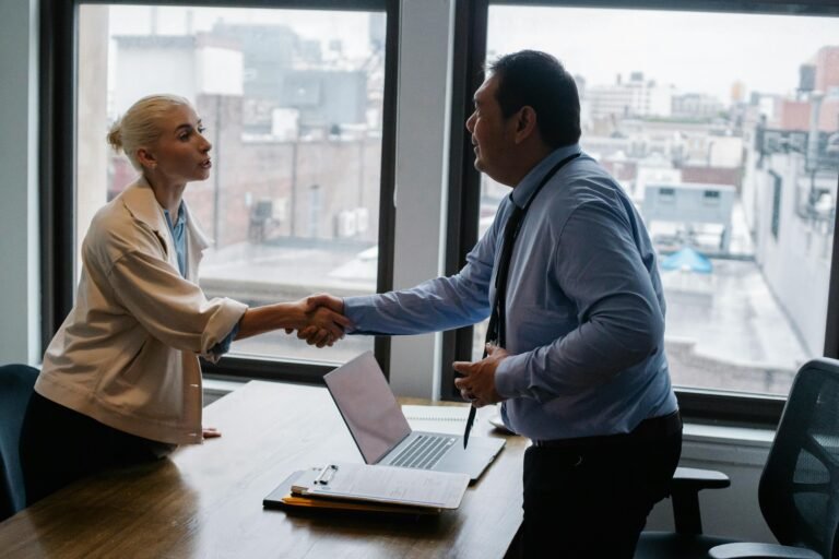 Two people in interview or meeting setting shaking hands