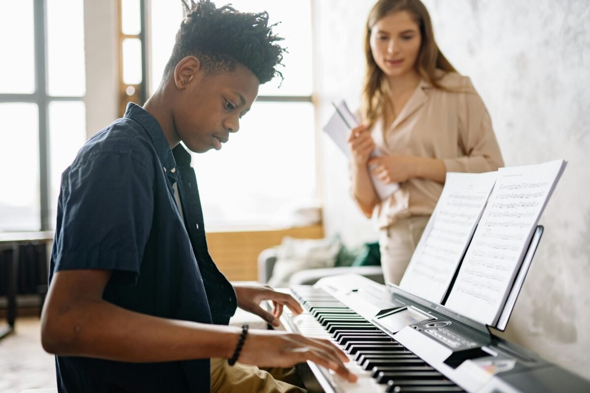 Music teacher with student playing piano