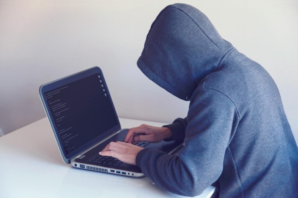 Man in hoodie sweater staring at laptop screen.