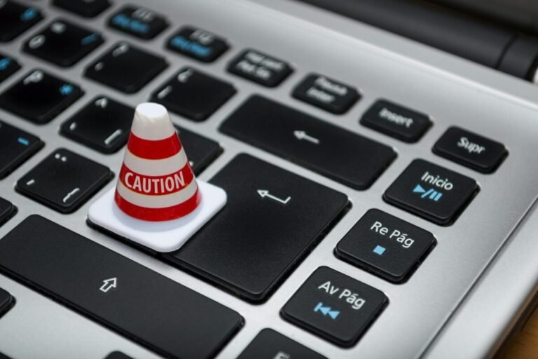 Caution cone sitting on the enter key of a laptop.
