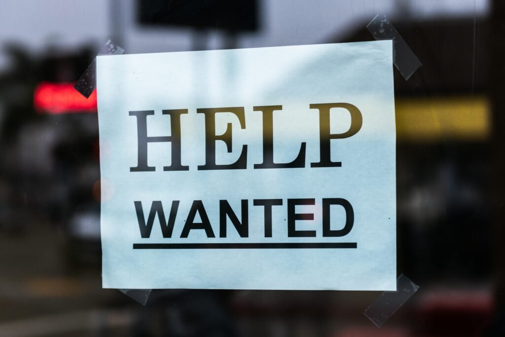 Help wanted sign behind glass.