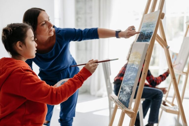 Art teacher with student pointing at canvas.
