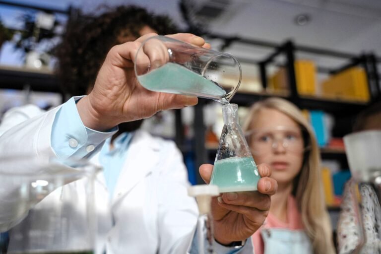 Science teacher holding up beakers for an experiment as students watch.