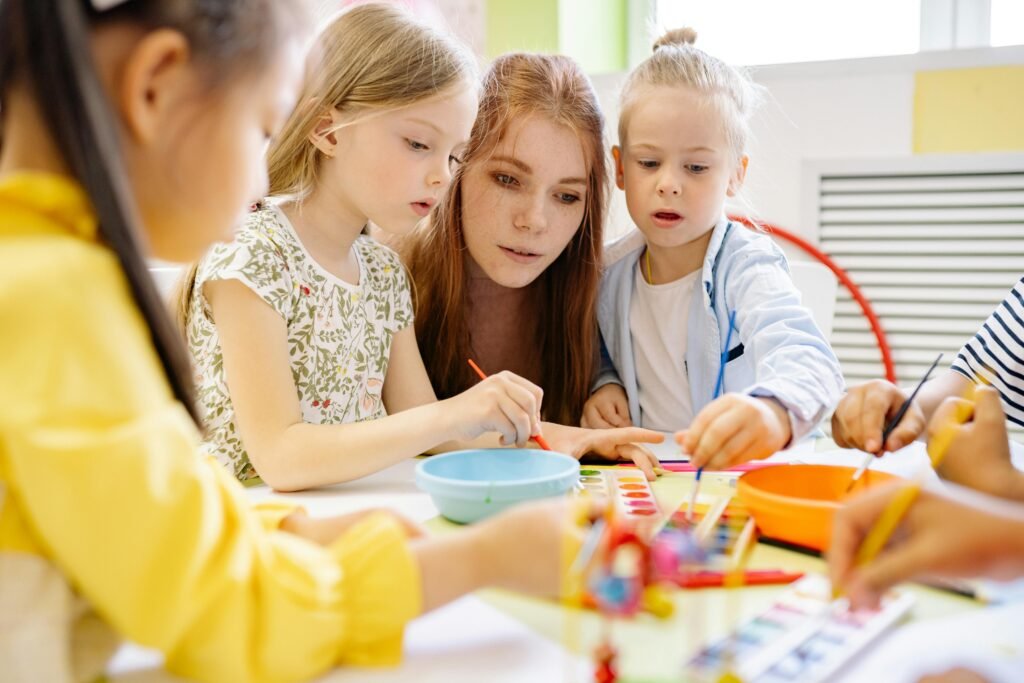 Preschool teacher with children at a table.