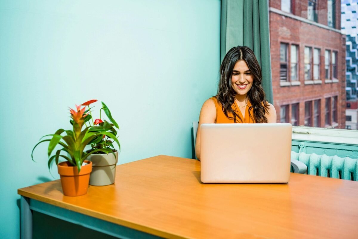 College support staff worker sitting at desk working on laptop.