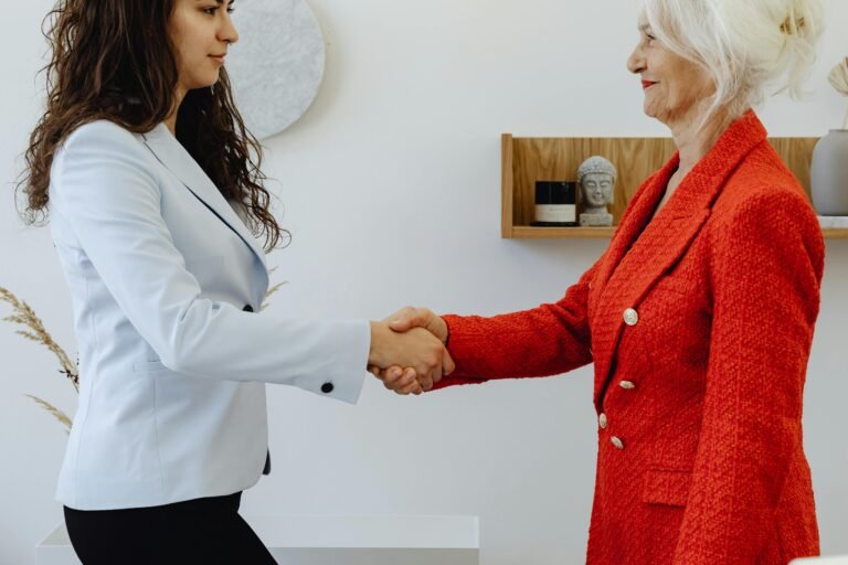 Two women shaking hands at the start of a school job interview.