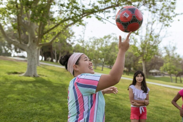 Summer camp counselor throwing ball in air.