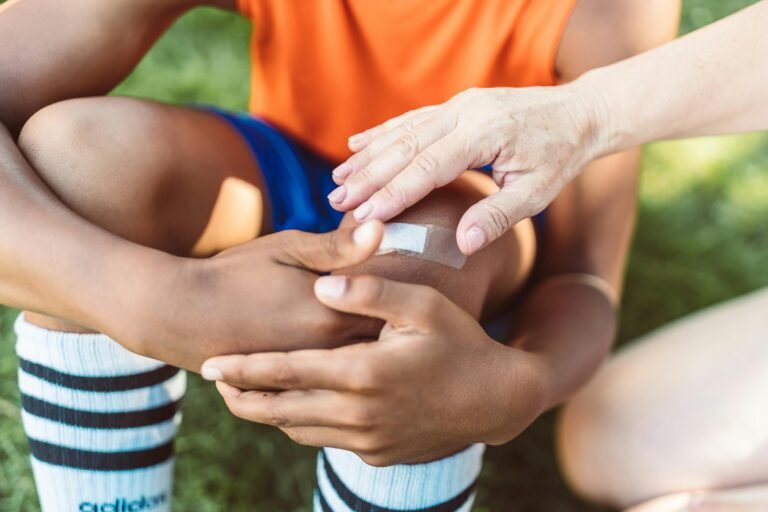 Nurse helping boy by putting on a band-aid.