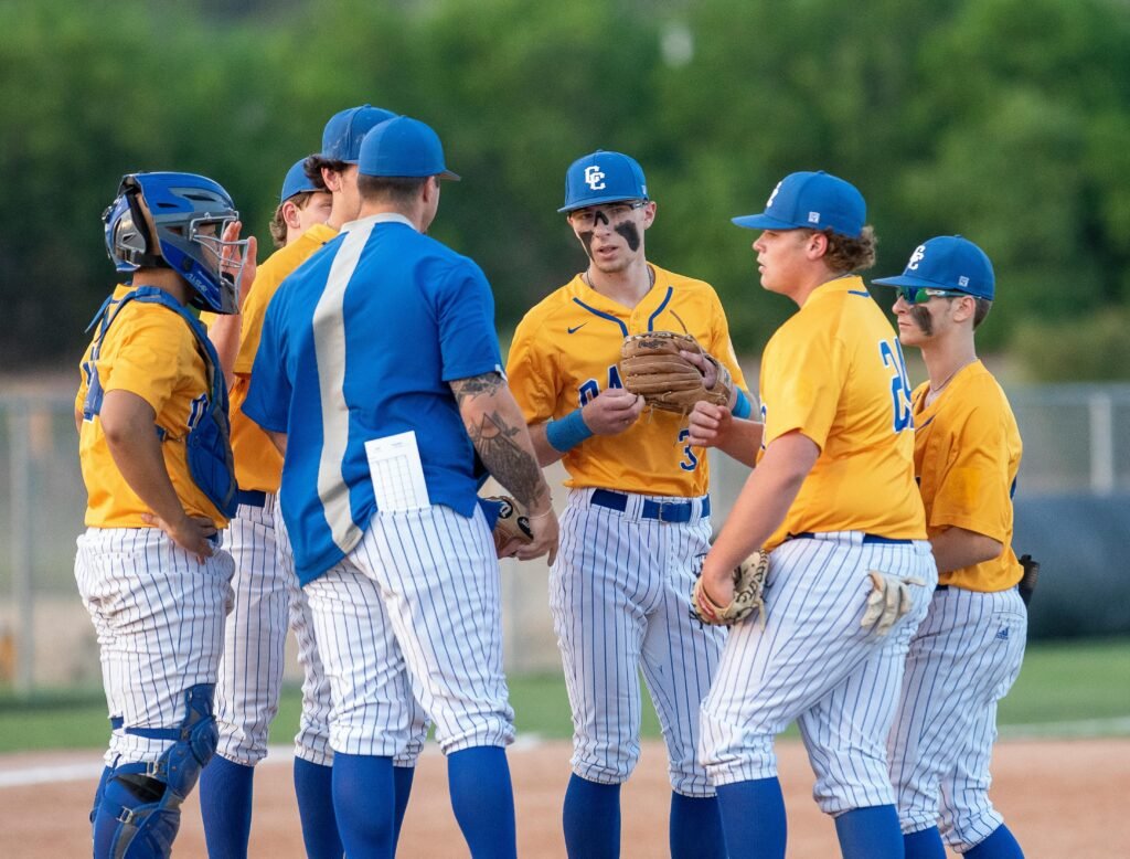 Baseball team coach speaking with baseball players.