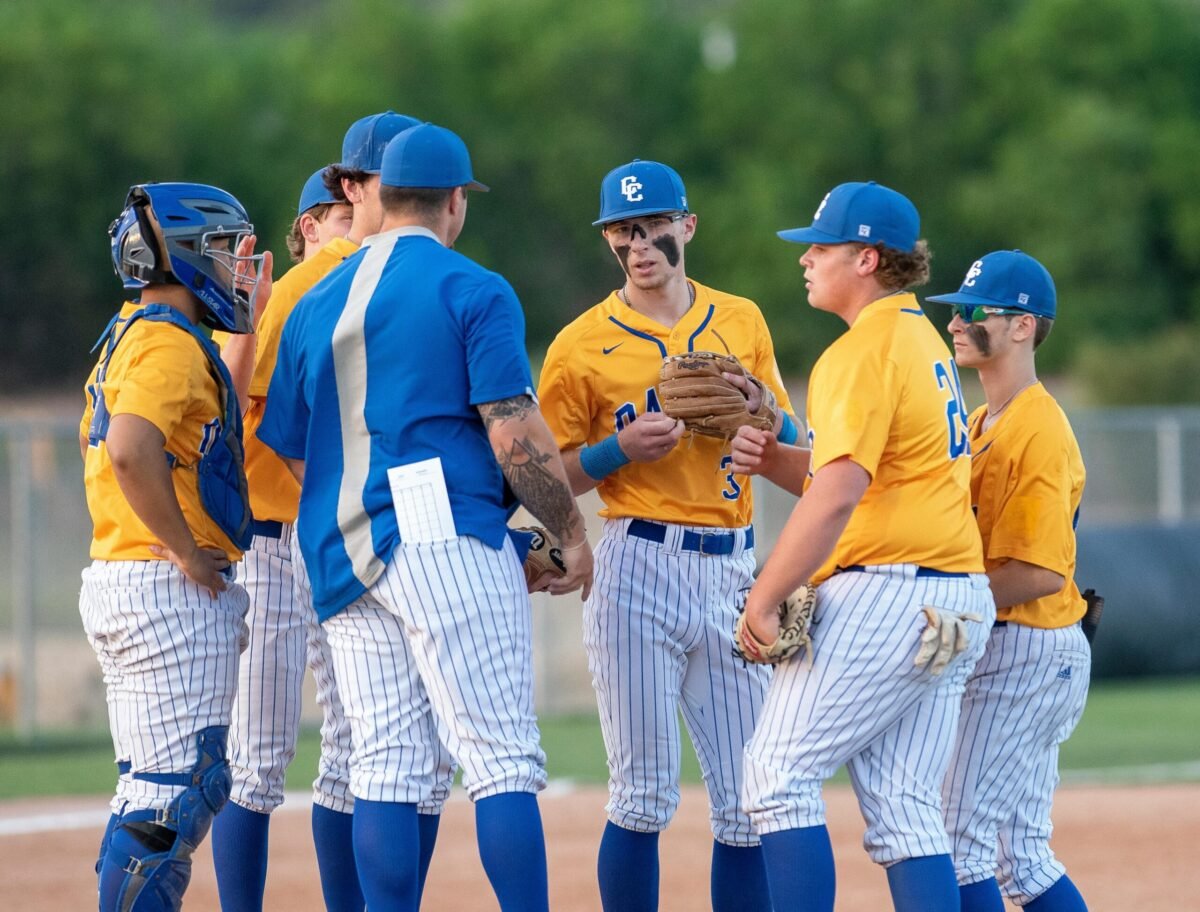Baseball team coach speaking with baseball players.