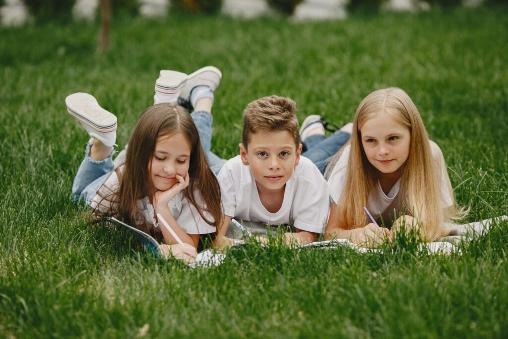 Summer campers on grass writing in their books.