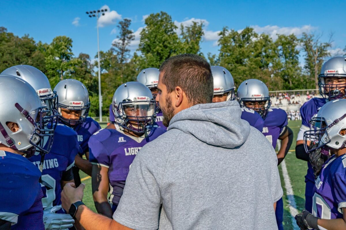 Junior varsity coach on the field with players.