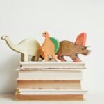 Dinosaur cut outs on top of pile of books.