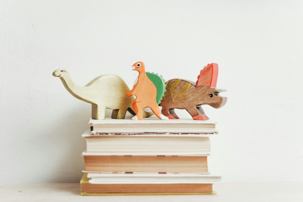 Dinosaur cut outs on top of pile of books.
