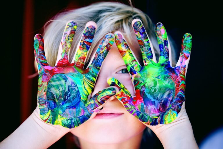 Elementary school student with paint all over his hands in art class.
