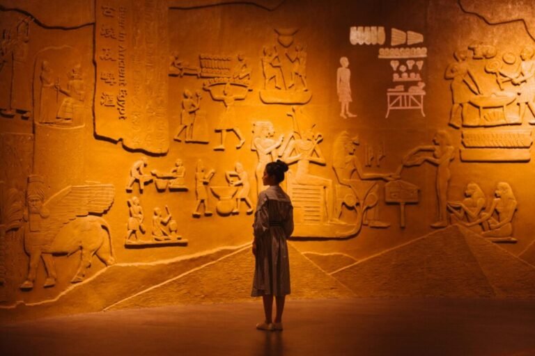 Woman reading Egyptian history on a wall written in hieroglyphs.